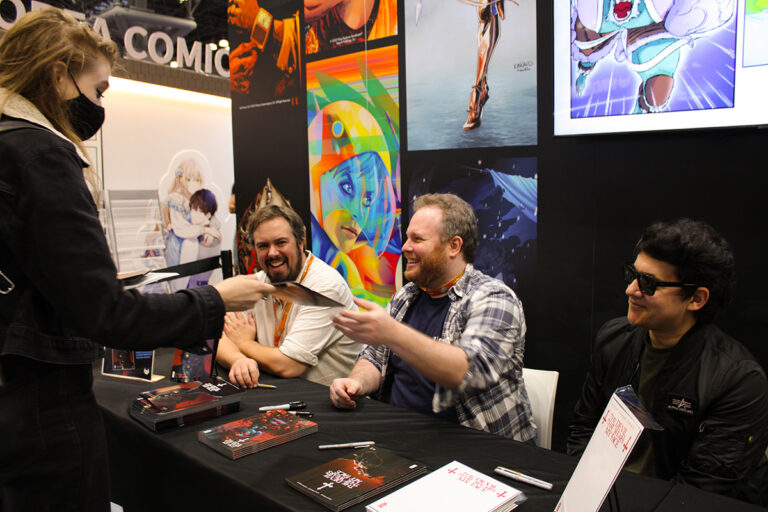Alex Cormack, David Pepose, and Maan House handing a signed copy of The Devil That Wears My Face to Sami ( @samidemonster)